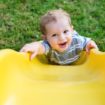 Young toddler boy child playing on slide at playground outdoors during summer