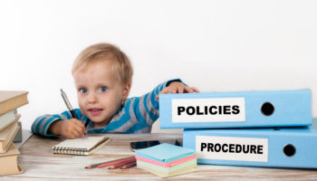 Policies and Procedure – young boy with stack of two office bind