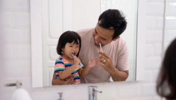 kid learn how to brush teeth with dad
