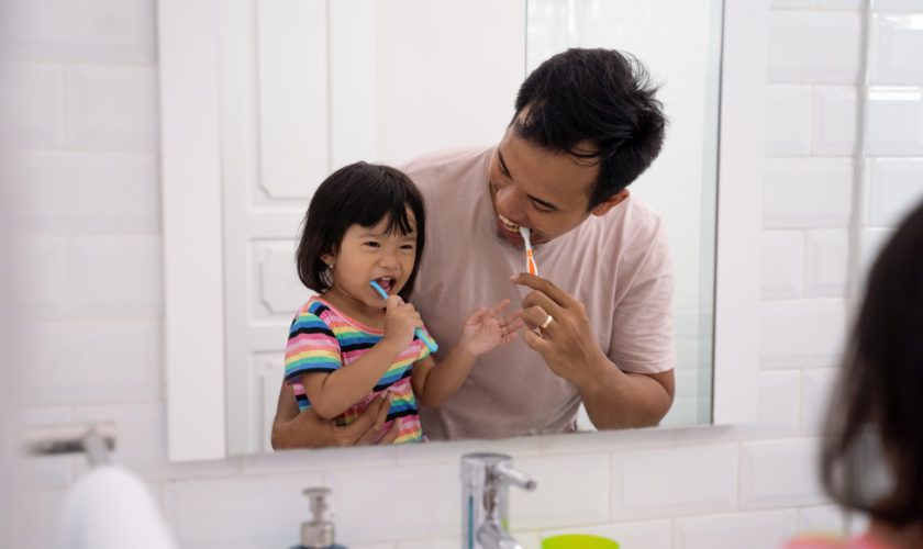 kid learn how to brush teeth with dad