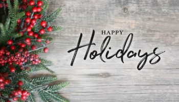 Happy Holidays Text with Holiday Evergreen Branches and Berries Over Rustic Wooden Background