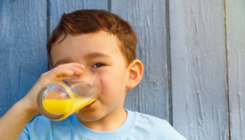 Kind kleiner Junge trinkt Orangensaft Saft trinken Textfreiraum Copyspace draußen