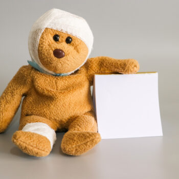 Teddy,Bear,With,Bandage,On,Gray,Background.