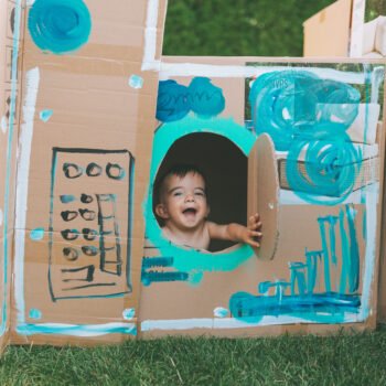 A happy baby in a painted cardboard box.