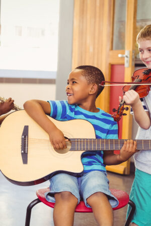 Smiling,Kids,Playing,Guitar,,Violin,,Flute,In,Classroom,At,School