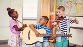 Smiling,Kids,Playing,Guitar,,Violin,,Flute,In,Classroom,At,School