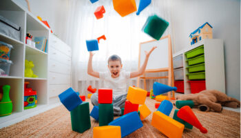 Boy,Child,Laughs,Sitting,On,Floor,Children’s,Room,,Throwing,Up