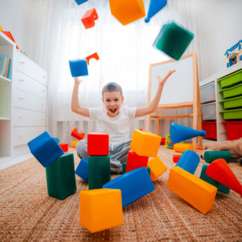 Boy,Child,Laughs,Sitting,On,Floor,Children’s,Room,,Throwing,Up